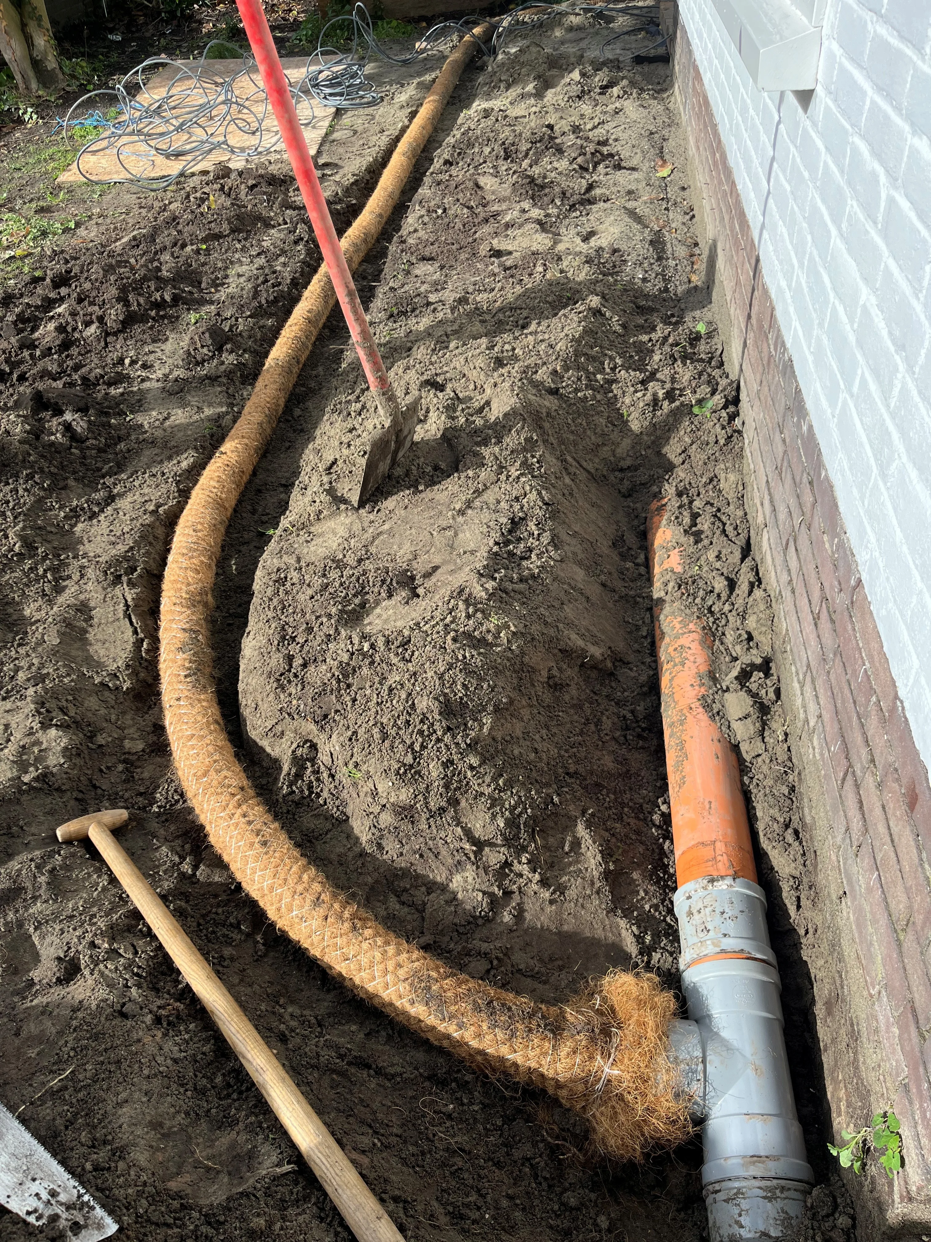 Aanleg van drainageleiding naast woning