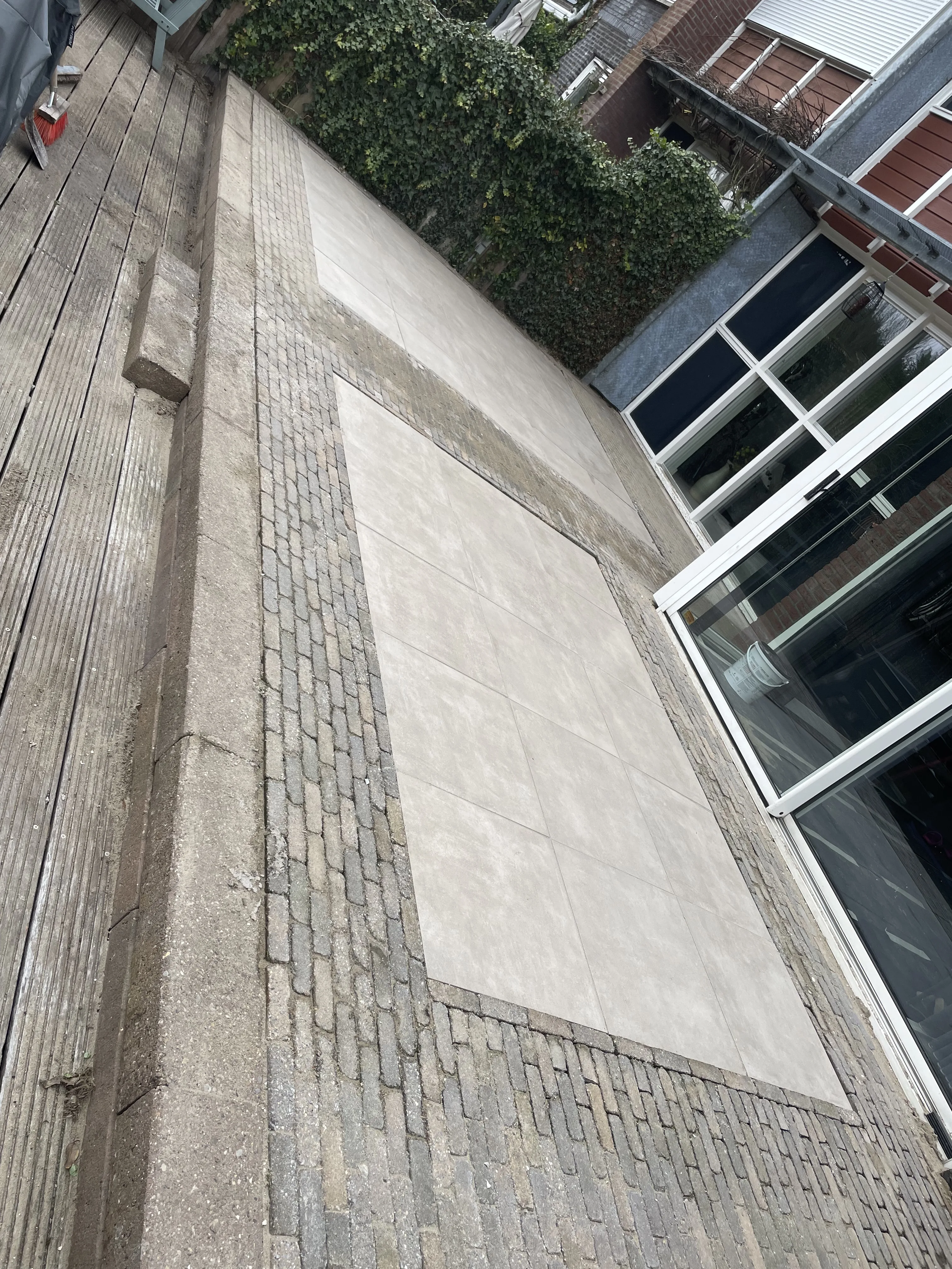 Combinatie van grote tegels en klinkers in een moderne tuin