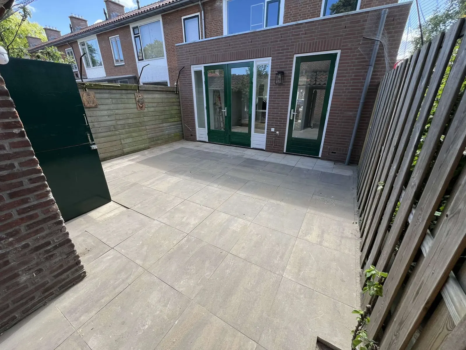 Complete achtertuin met grote tegels – hovenierswerk van Herfst Sierbestrating in Noordeinde